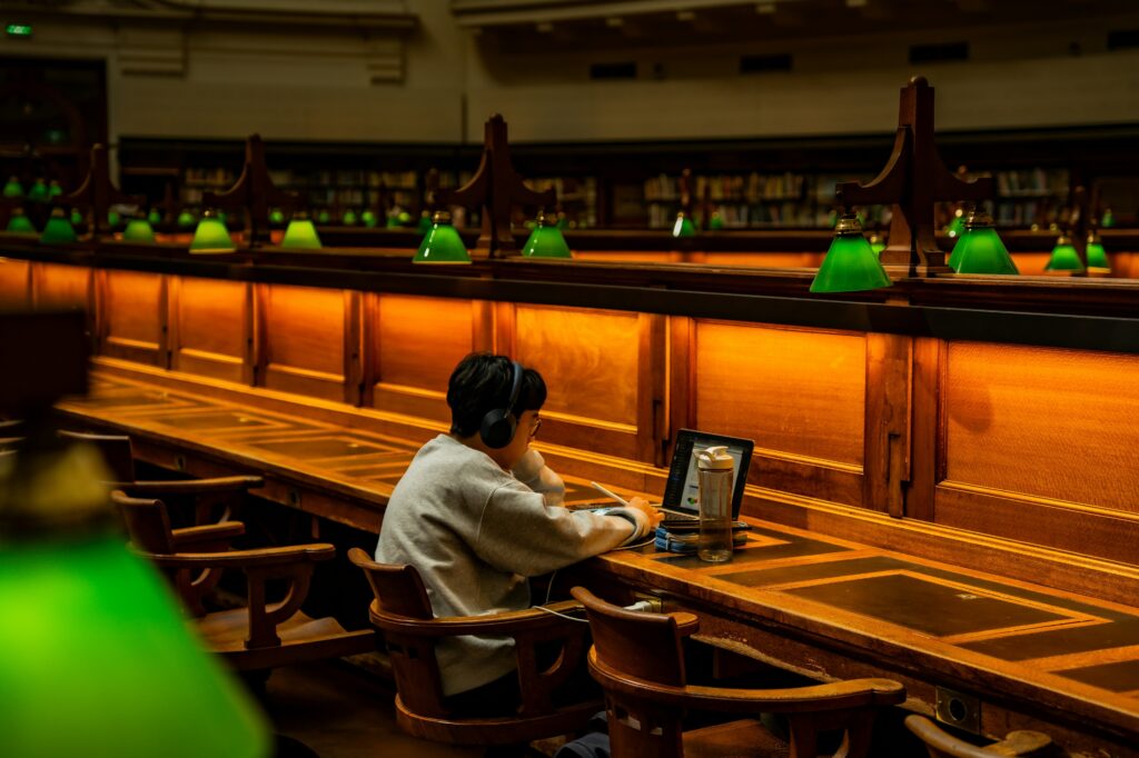 student in a university library working on laptop